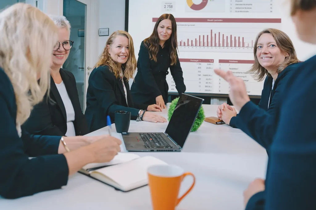 En gruppe forretningsfolk som sitter rundt et konferansebord og diskuterer bedriftsprogrammer.