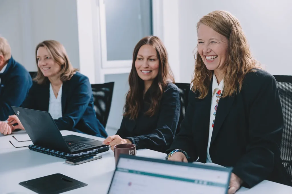 En gruppe forretningsfolk som sitter rundt et konferansebord og diskuterer strategi og veivalg.