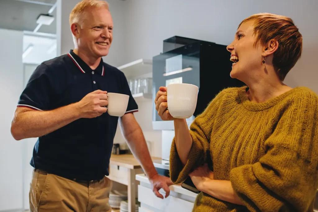 Et par nyter kaffe på et koselig kjøkken.