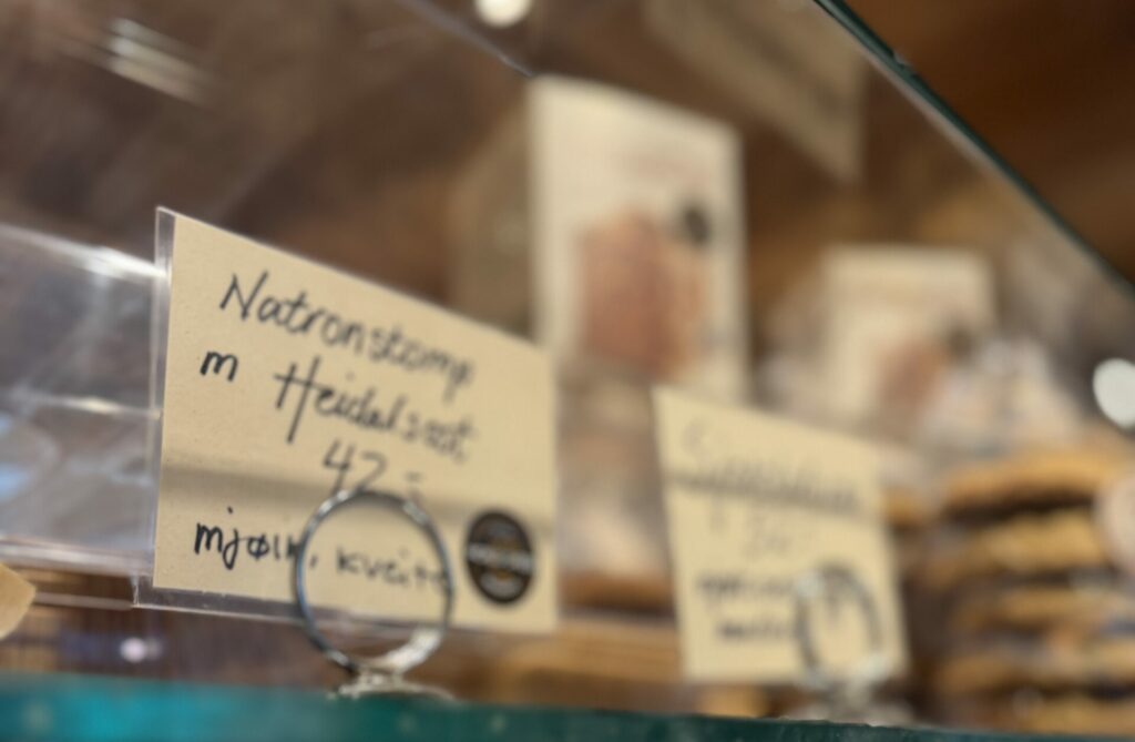 Et vitrineskap med håndskrevne etiketter fra Heidal Ysteri.